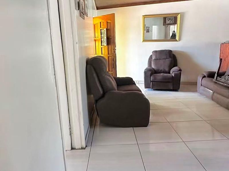 A living room featuring large format floor tiles and a timber tongue and groove ceiling.