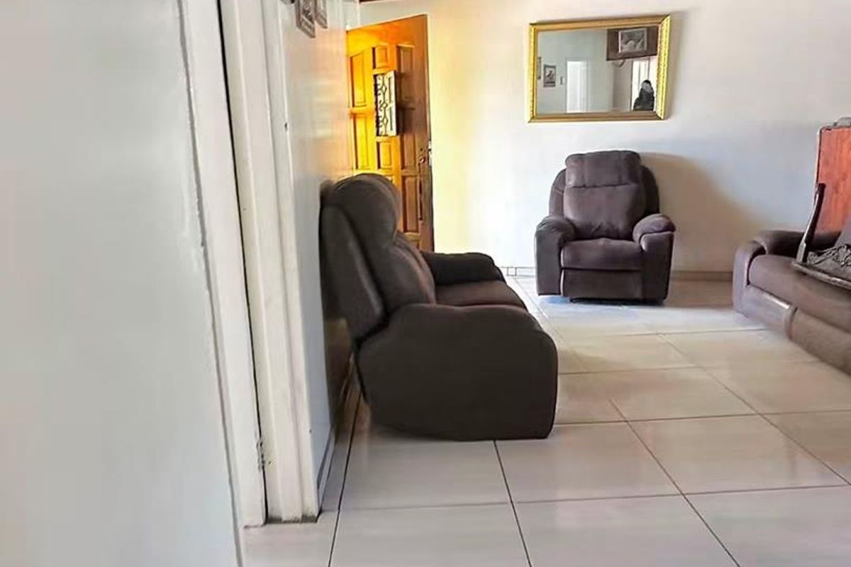 A living room featuring large format floor tiles and a timber tongue and groove ceiling.