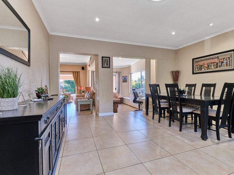 Spacious dining area featuring neutral tiled flooring and recessed lighting, with an open-plan layout connecting to the adjacent living spaces.