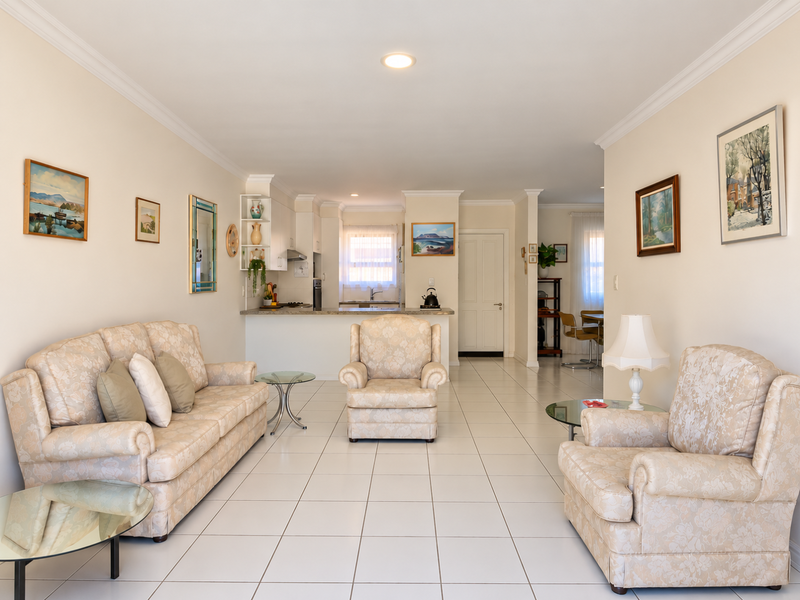 Spacious open-plan living area featuring tiled flooring, recessed lighting, and a functional kitchen with built-in cabinetry and countertops.