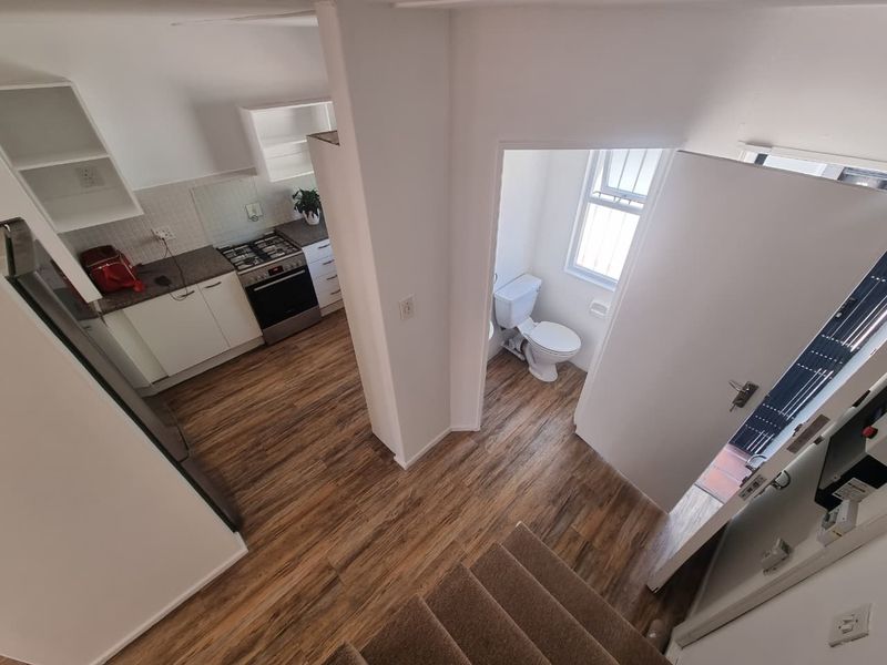 Open-plan kitchen with modern cabinetry and gas hob, adjacent to a ground-floor guest toilet, featuring durable laminate flooring and direct access to the entrance.