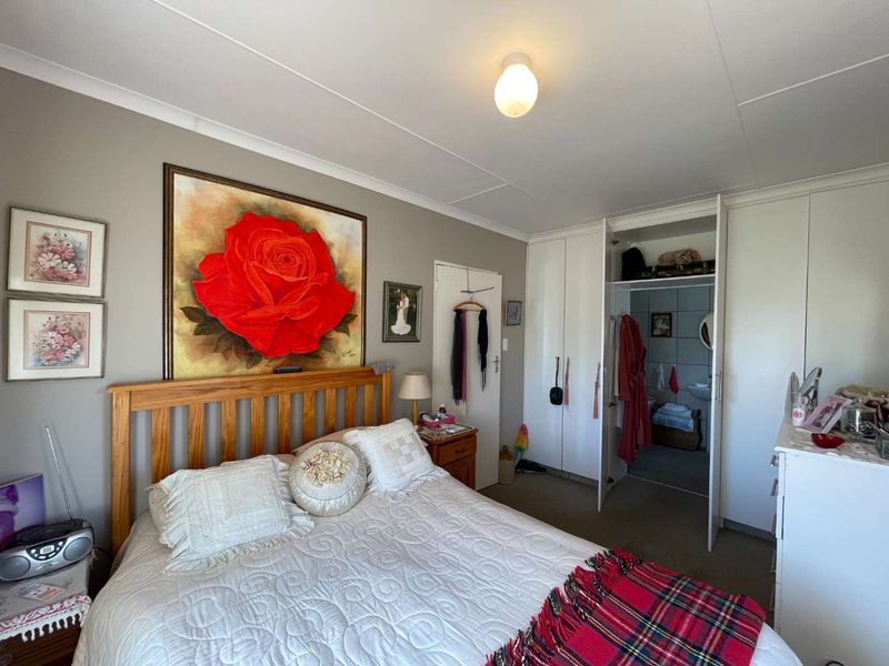 A functional bedroom featuring built-in cupboards and direct access to an en-suite bathroom, offering a practical layout with neutral wall finishes.