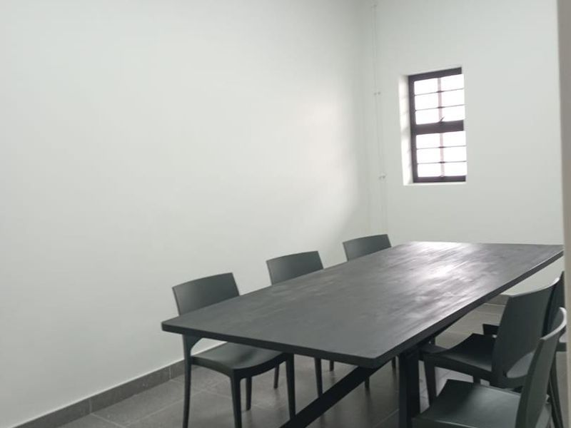 A clean, functional office space featuring tiled flooring, recessed ceiling lighting, and a security-barred window, suitable for professional use.
