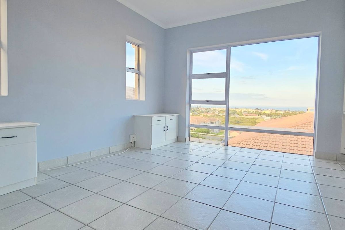 A bright, empty bedroom featuring tiled flooring, built-in cabinetry, and large windows offering expansive views.