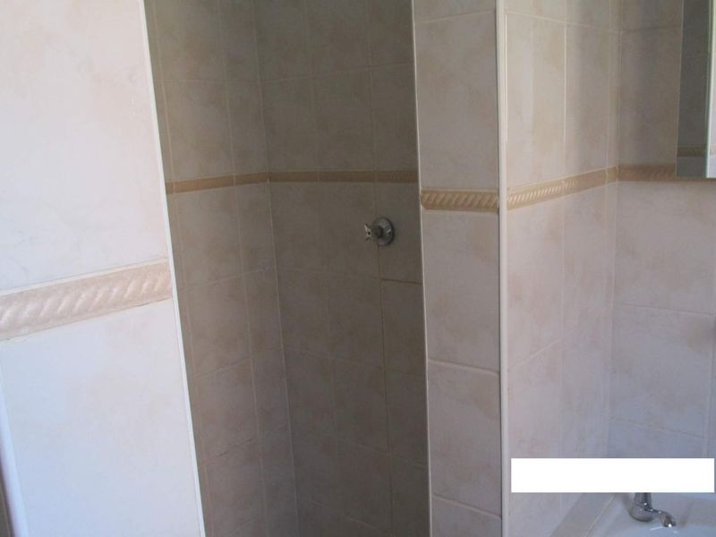 A functional bathroom featuring a tiled shower enclosure and a bathtub with standard fixtures.