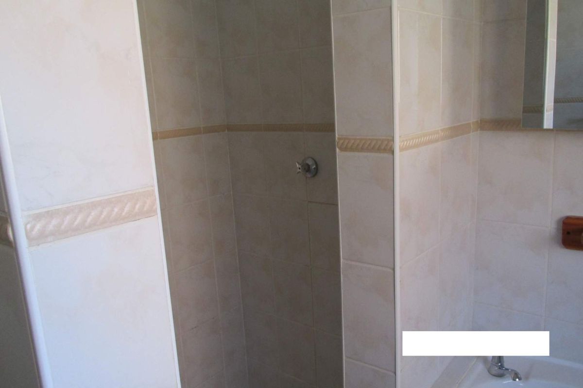 A functional bathroom featuring a tiled shower enclosure and a bathtub with standard fixtures.