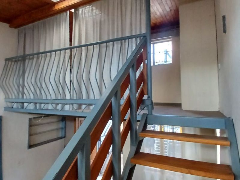 A mezzanine level living area featuring a timber ceiling, skylight, and a metal staircase with timber treads.