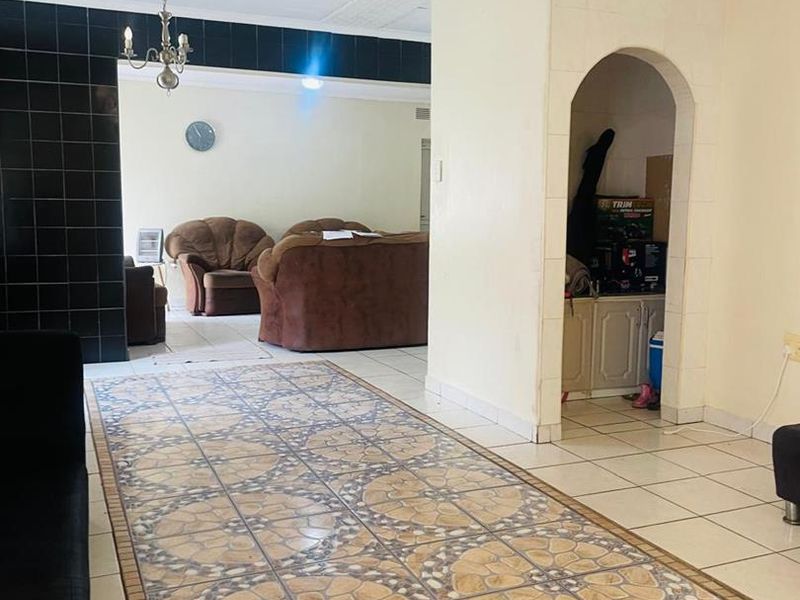 Open plan living area featuring decorative ceramic floor tiles, a distinct arched entryway, and a black tiled feature wall.