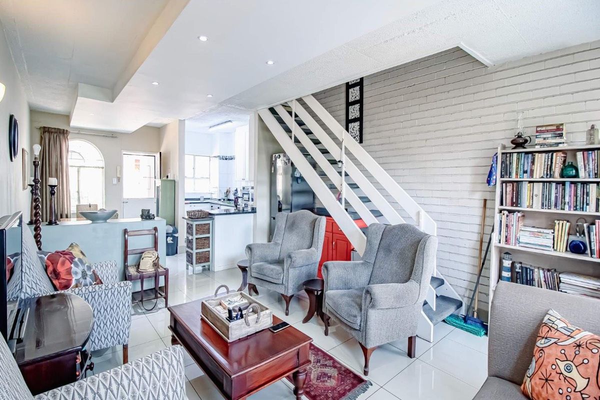 Open plan living area featuring a staircase, tiled flooring, and a connected kitchen space with neutral finishes.