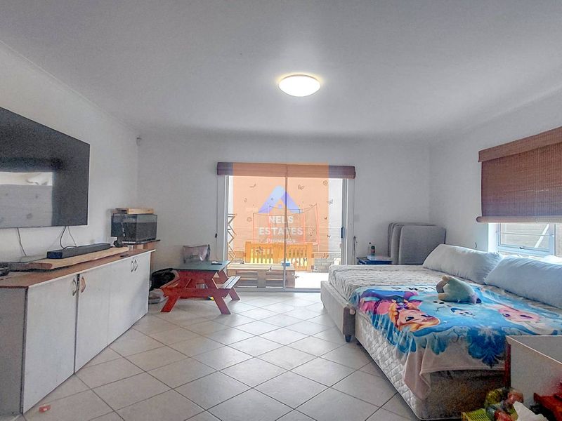 A spacious living area featuring tiled flooring, built-in storage cabinetry, and a sliding glass door providing access to the outdoor patio area.