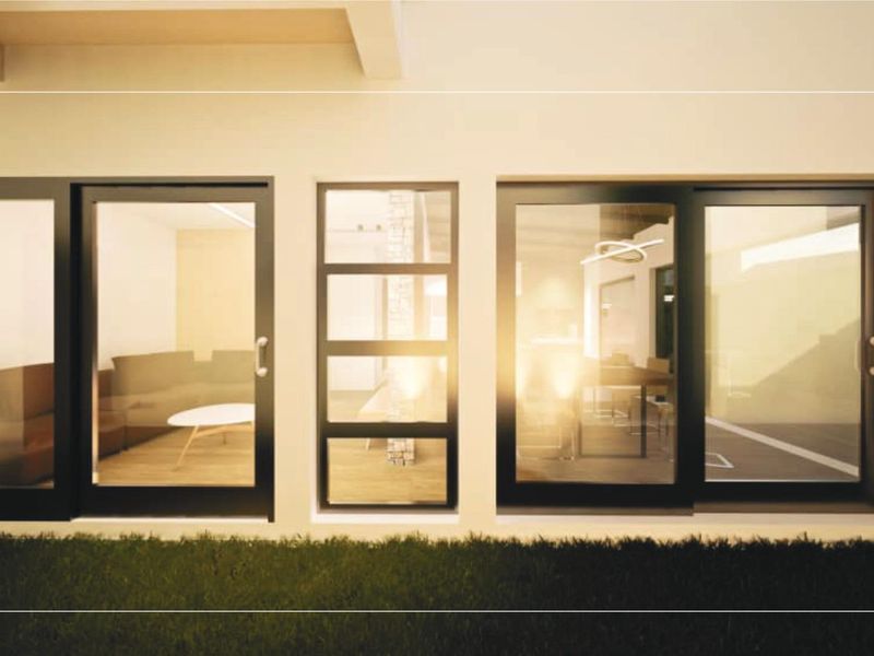 Rear exterior view of a townhouse featuring modern black-framed sliding glass doors and a central fixed glass panel.