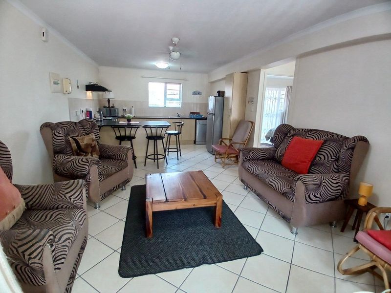 Open-plan living and kitchen area featuring tiled flooring, a breakfast bar, and functional kitchen cabinetry.