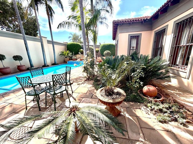 A well-maintained outdoor pool area featuring a paved patio, established landscaping, and a swimming pool, adjacent to the main house structure.