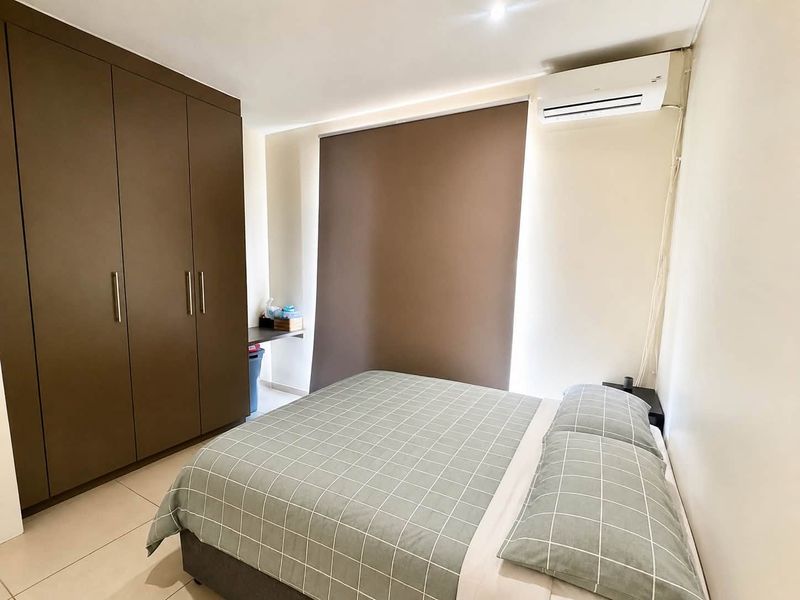 A well-maintained bedroom featuring built-in cupboards, tiled flooring, and a wall-mounted split-system air conditioner for climate control.