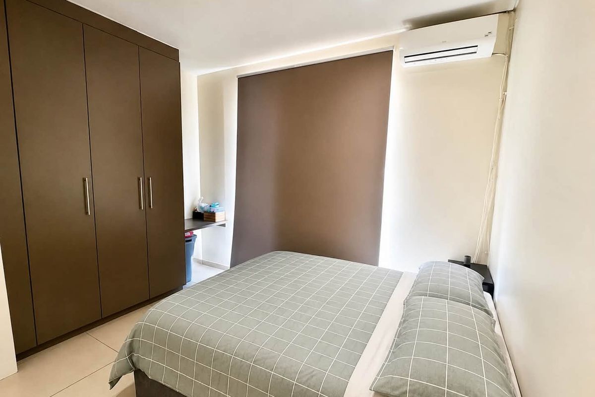 A well-maintained bedroom featuring built-in cupboards, tiled flooring, and a wall-mounted split-system air conditioner for climate control.