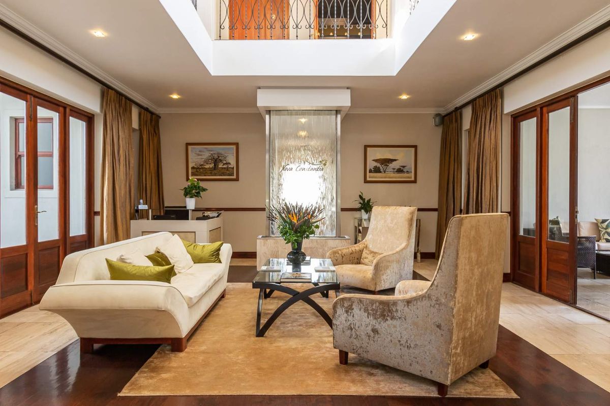 Elegant guest house reception area featuring a central water feature, high ceilings with a skylight, and polished flooring.