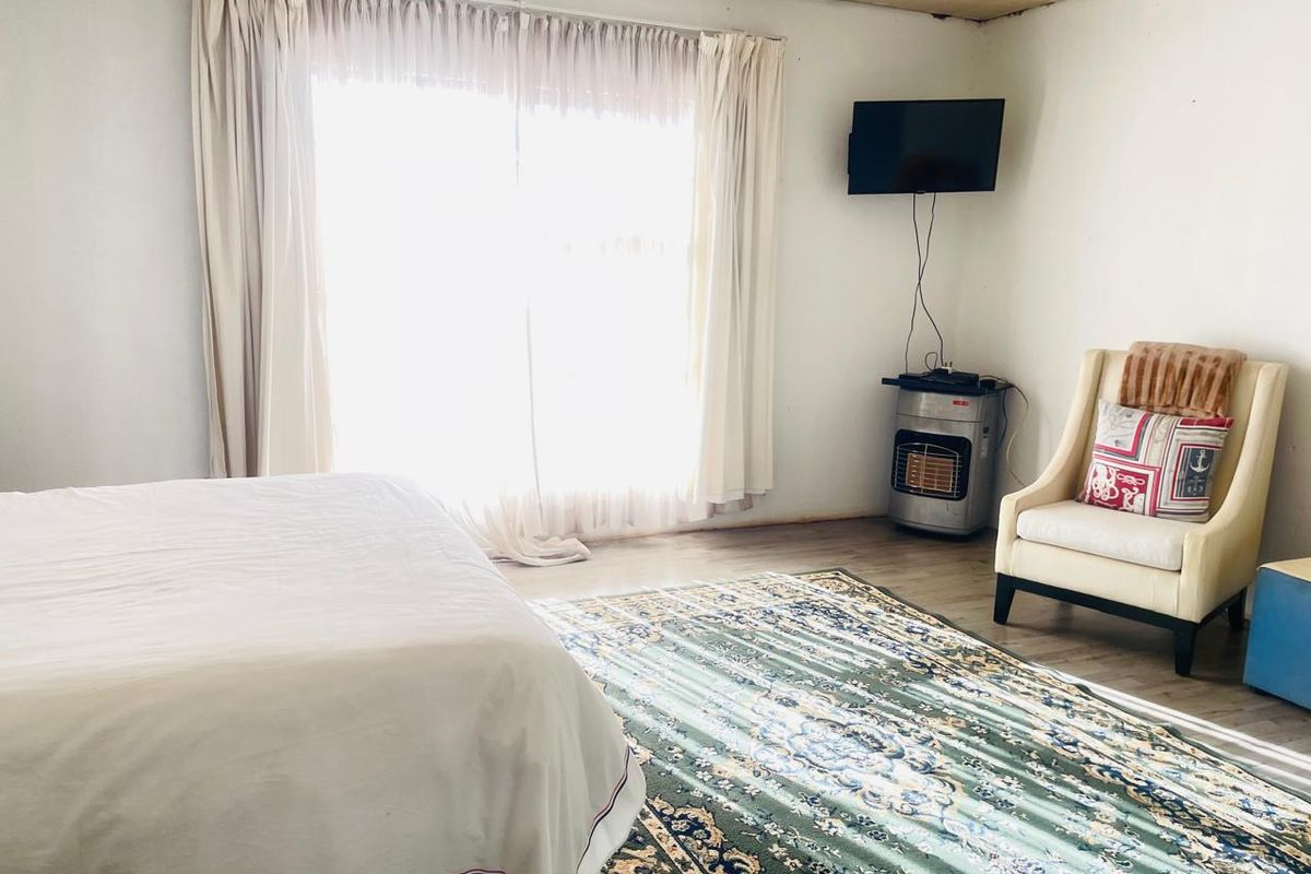 A bedroom featuring large sliding glass doors with curtains, light-colored flooring, and a neutral wall finish.