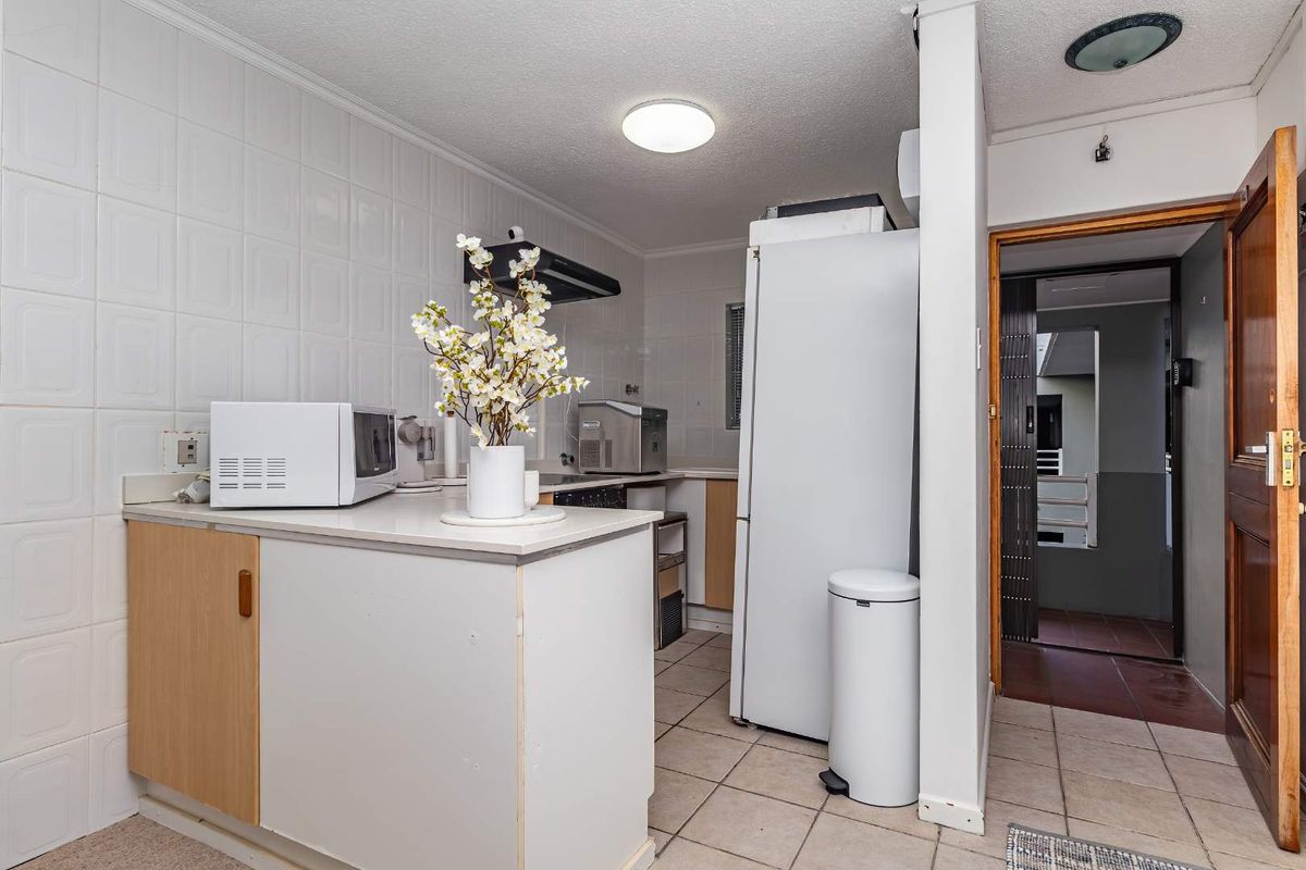 A functional kitchen featuring tiled walls, built-in cabinetry, and a compact layout, providing a practical space for meal preparation.