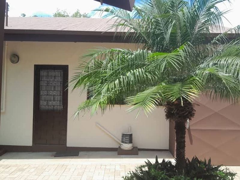 A paved rear patio area featuring a security door and exterior wall lighting, providing a functional outdoor space.