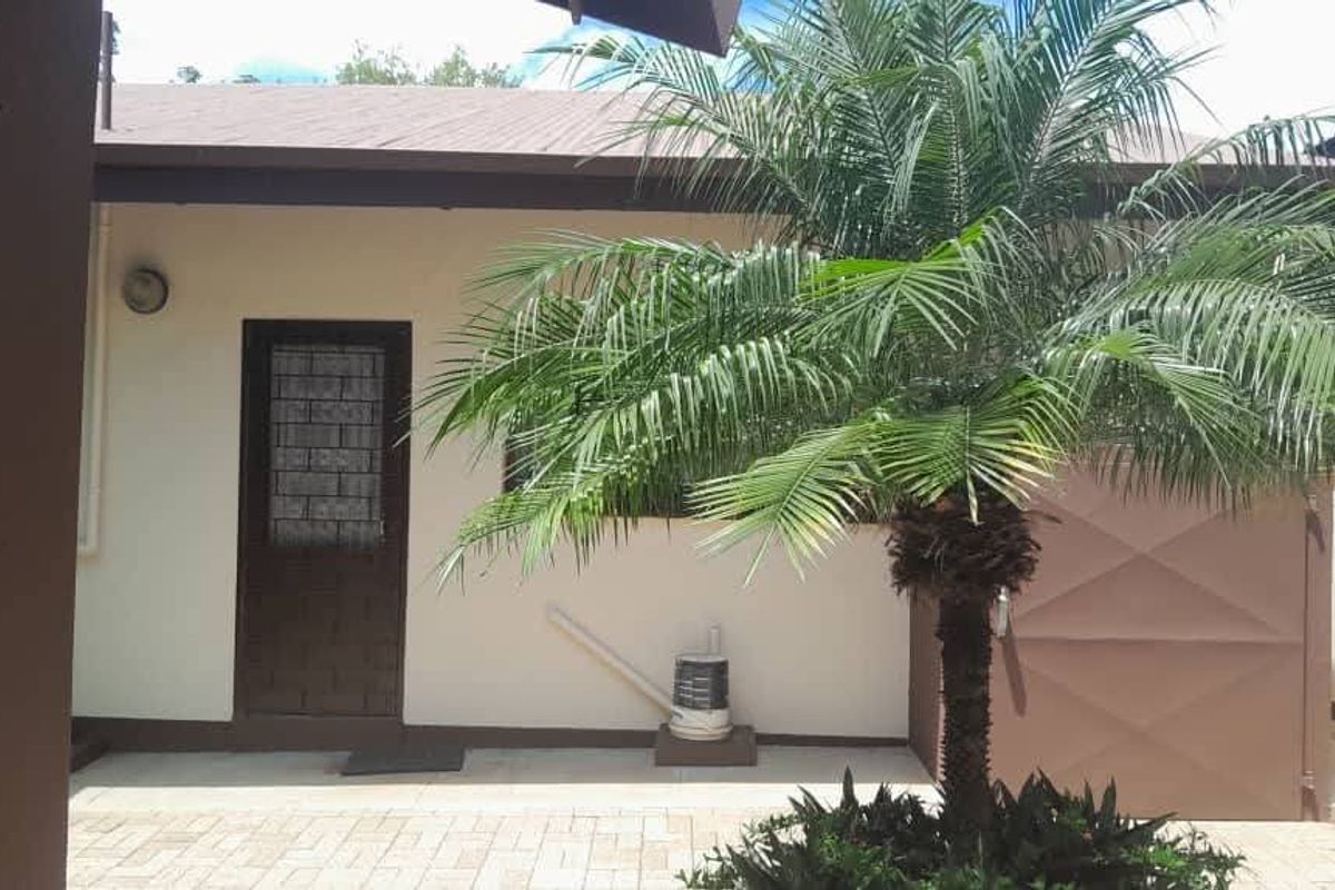 A paved rear patio area featuring a security door and exterior wall lighting, providing a functional outdoor space.