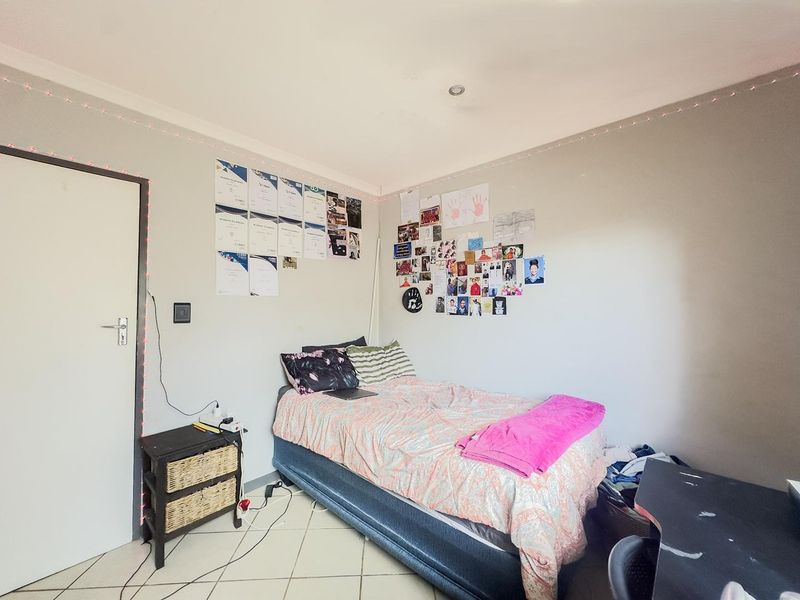 A functional bedroom featuring tiled flooring and recessed ceiling lighting, providing a neutral base for personalization.