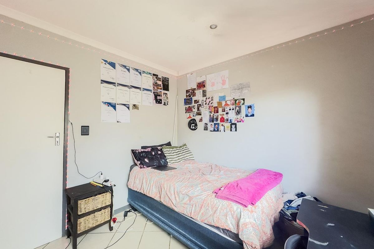 A functional bedroom featuring tiled flooring and recessed ceiling lighting, providing a neutral base for personalization.