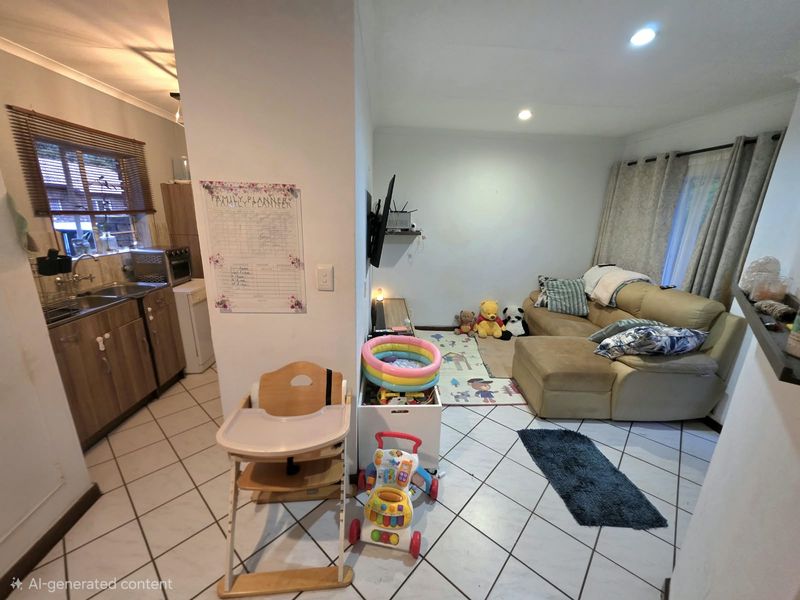 Open-plan living and kitchen area featuring tiled flooring, functional cabinetry, and recessed lighting, offering a versatile space for daily living.