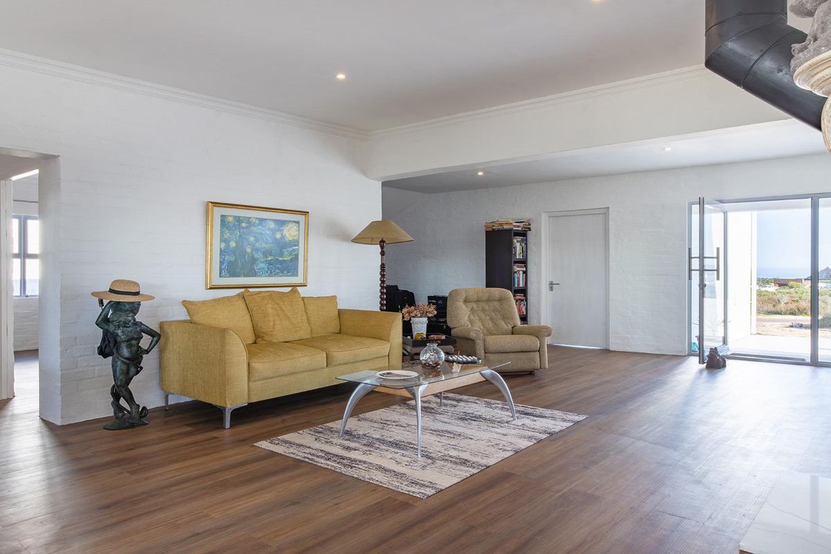 Spacious living room featuring wood-look flooring, painted brick walls, recessed lighting, and a prominent fireplace with an exposed flue.