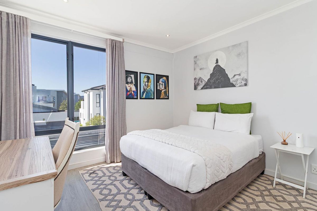 A bright and modern bedroom featuring large windows, neutral flooring, and recessed ceiling lighting, offering a comfortable and well-maintained living space.