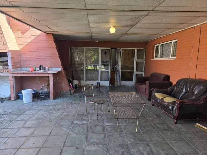 Covered outdoor patio area featuring a built-in brick braai, tiled flooring, and direct access to the home interior.