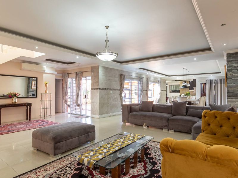 Spacious open-plan living area featuring tiled floors, a stone accent wall, recessed ceiling lighting, and seamless flow to the dining and kitchen spaces.