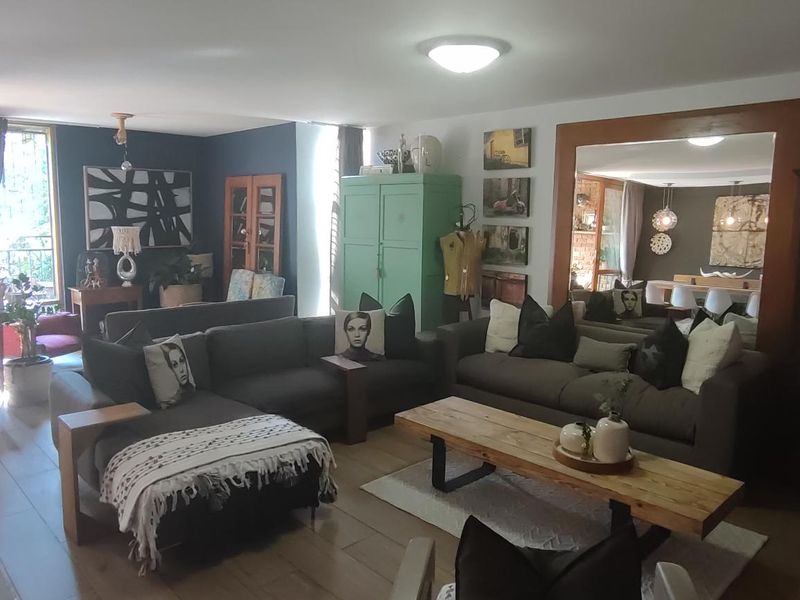 Spacious living room featuring wood-look flooring and a large wall-mounted mirror, creating an open and reflective atmosphere.