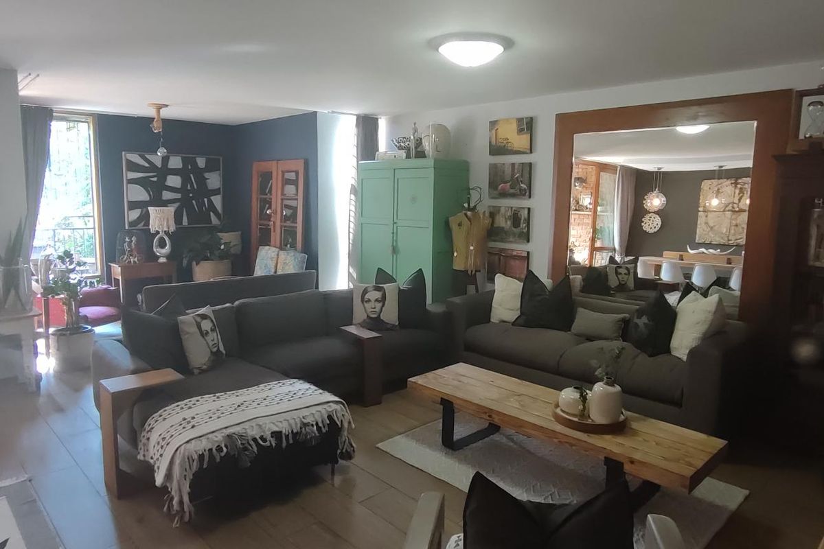 Spacious living room featuring wood-look flooring and a large wall-mounted mirror, creating an open and reflective atmosphere.
