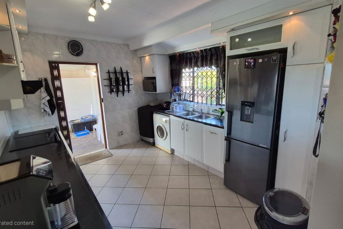 Functional kitchen featuring tiled flooring, ample built-in cabinetry, a double sink, and a security gate on the window.