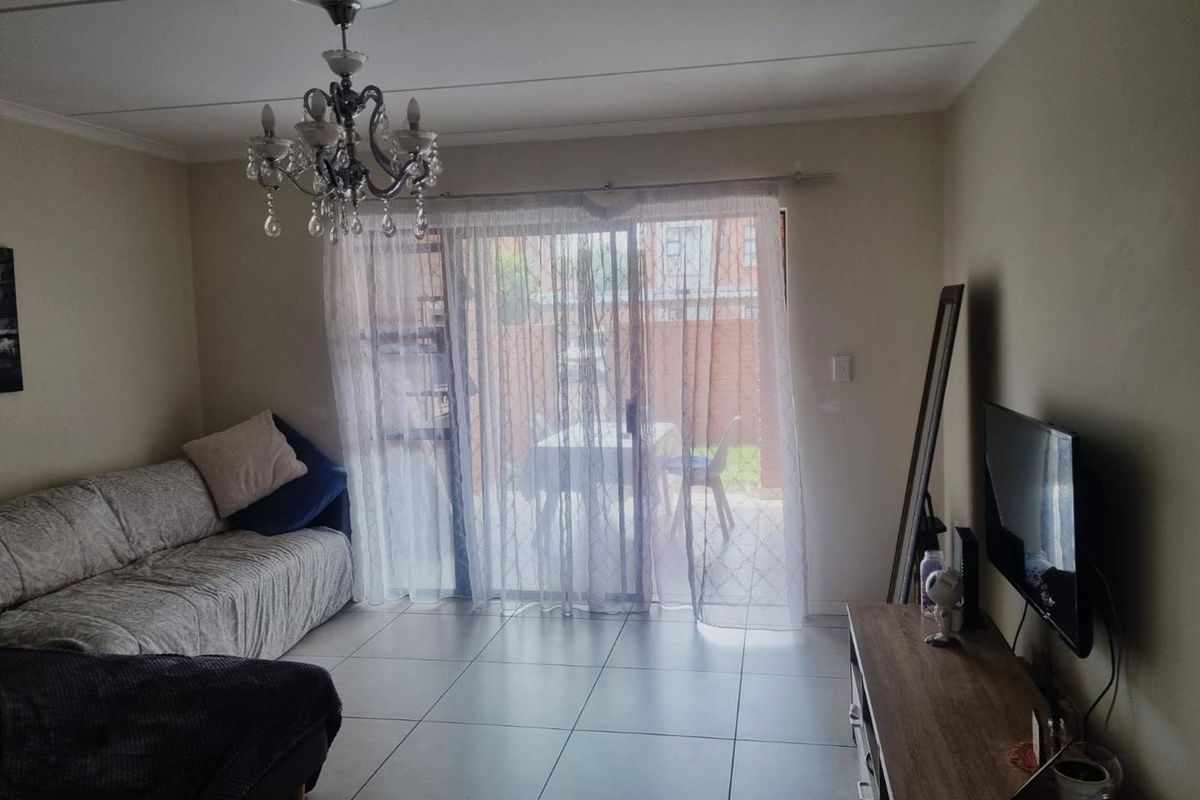 A living room featuring tiled flooring and a large sliding glass door that provides access to an outdoor patio area.