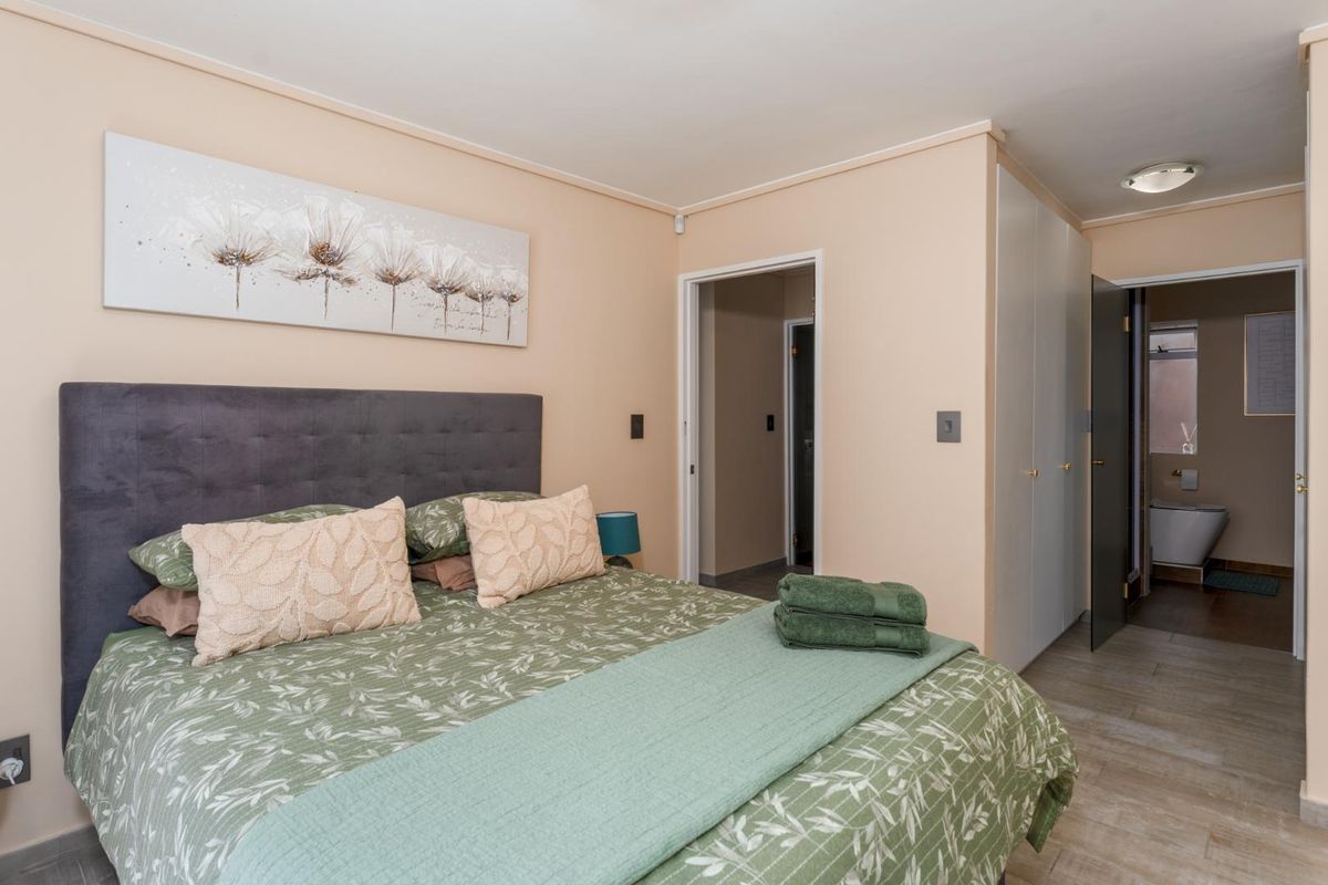 A bedroom featuring built-in cupboards and tiled flooring, with an adjoining bathroom visible through the doorway.