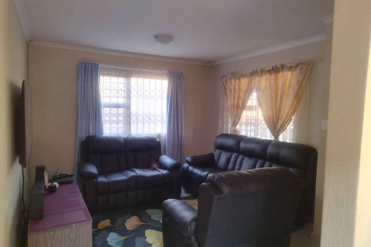 A functional living room featuring dual windows with security bars and coved ceilings, providing a comfortable and secure space for relaxation.