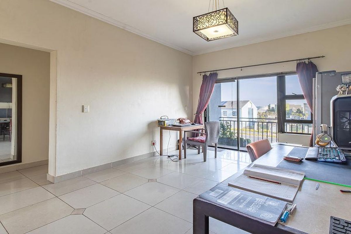 A living area featuring tiled flooring, a decorative pendant light, and a sliding glass door providing access to an outdoor balcony.