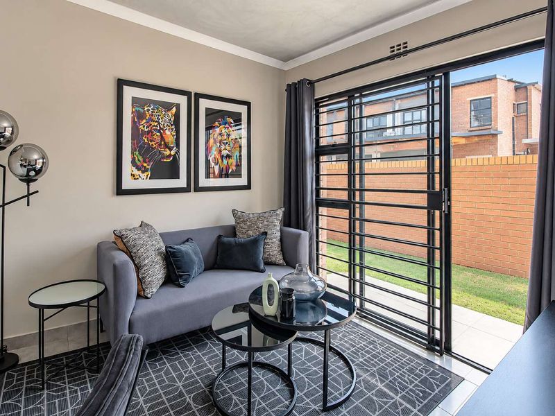 A well-maintained living area featuring tiled flooring, a sliding glass door with security gate, and direct access to an outdoor patio space.