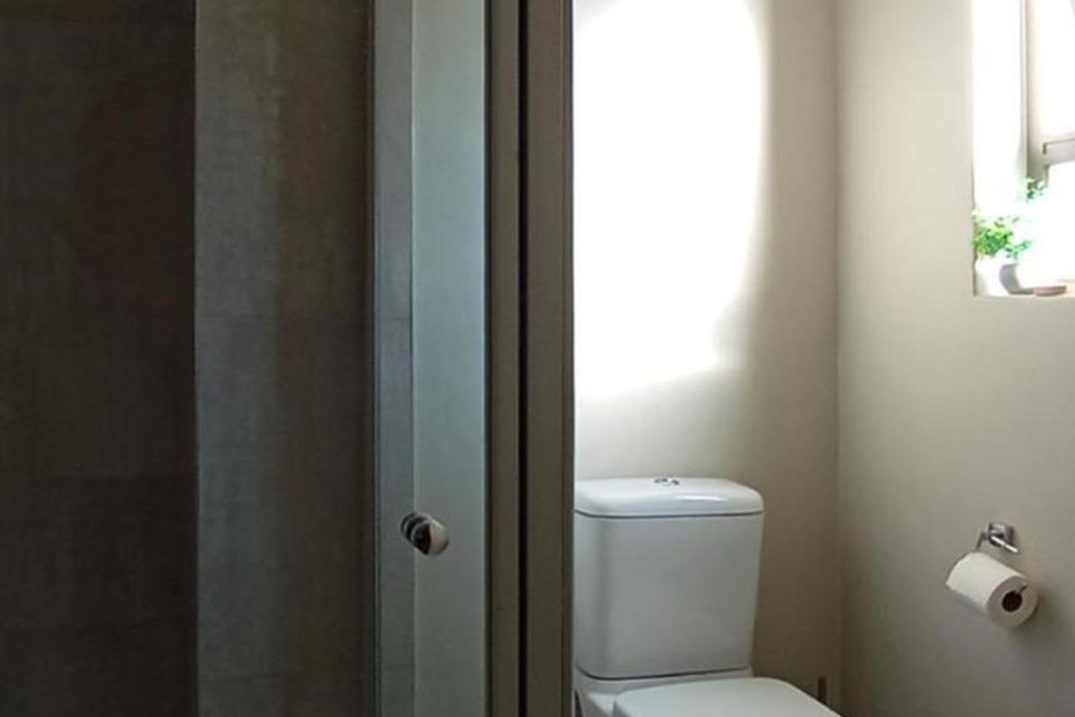 A functional bathroom featuring a glass-enclosed shower and a standard toilet, finished with neutral wall tones and tiled flooring.
