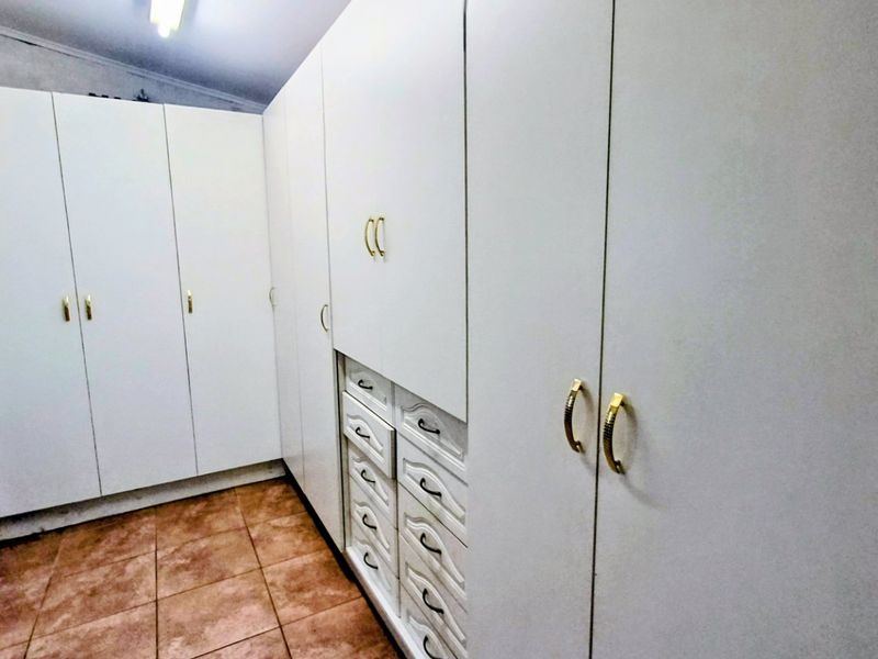 A bedroom featuring extensive built-in white cabinetry with integrated drawers and tiled flooring.