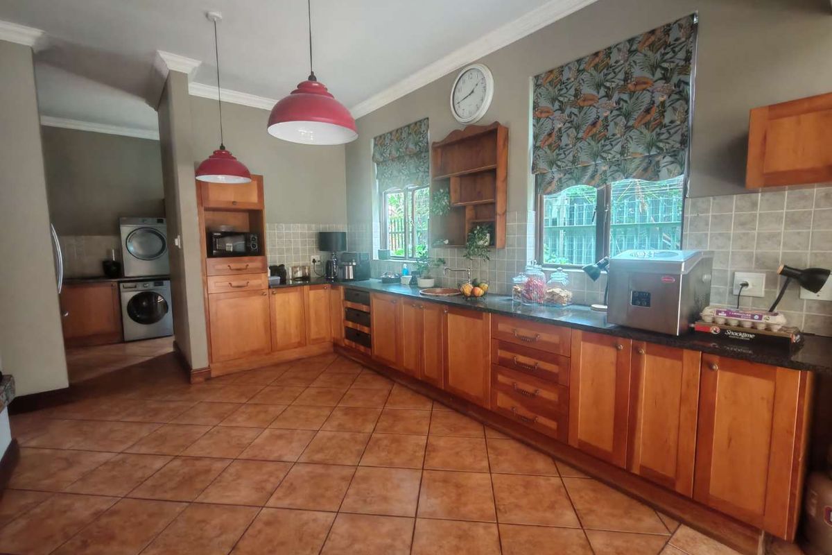 Spacious kitchen featuring wooden cabinetry, dark countertops, tiled flooring, and a dedicated laundry area visible in the background.