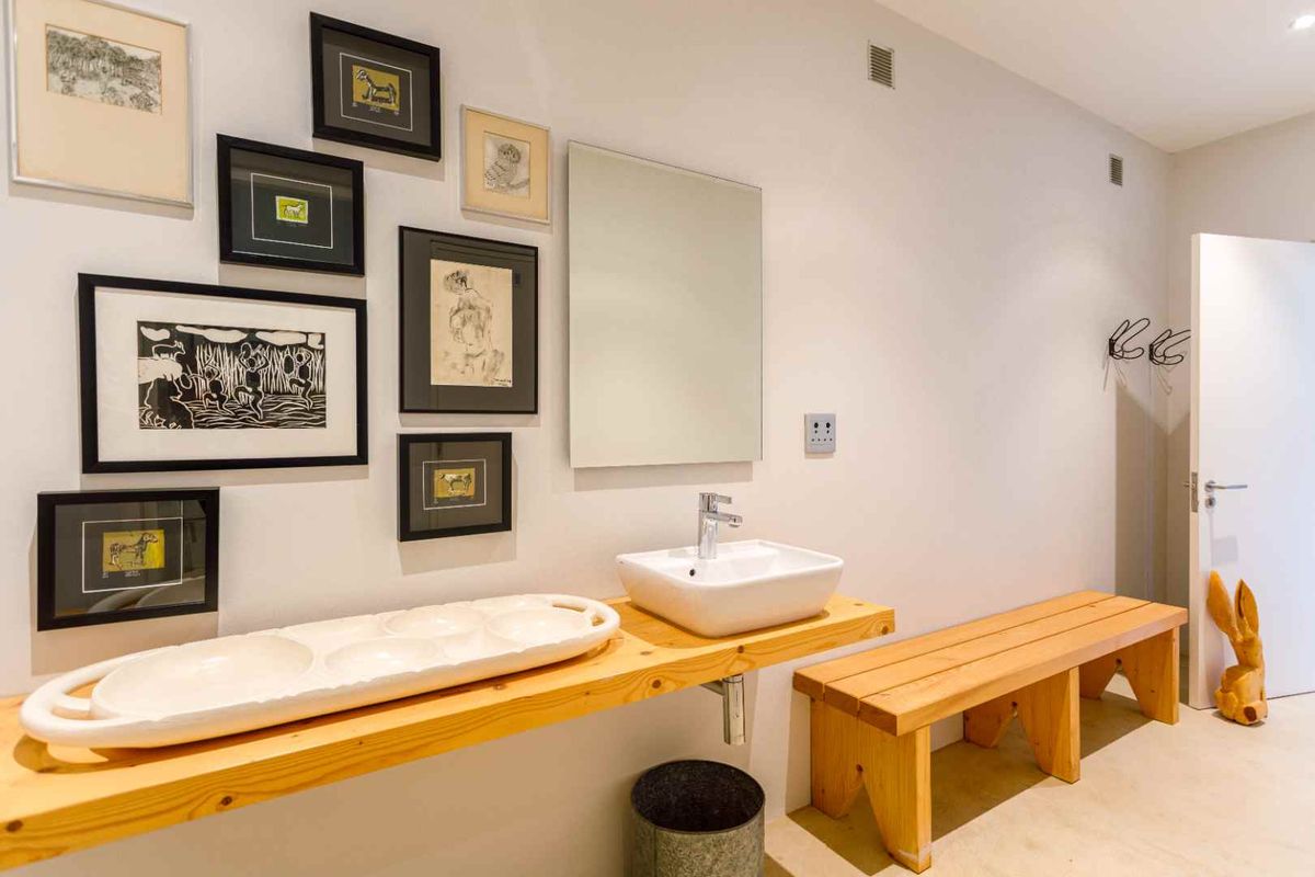 A modern bathroom featuring a wall-mounted timber vanity with a vessel sink, a frameless mirror, and clean, minimalist finishes.