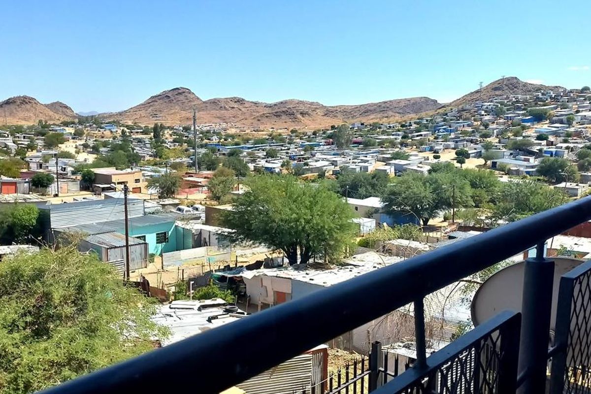 Elevated view overlooking the surrounding residential area and hills, captured from a balcony with a metal railing.