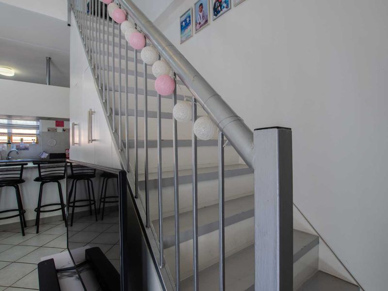 Open plan living area featuring a staircase with metal balustrade and an adjacent kitchen area with tiled flooring.