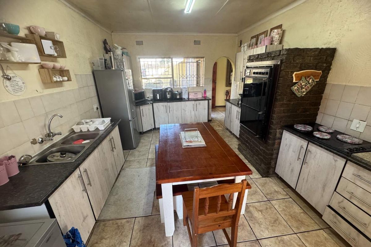 A functional kitchen featuring built-in cabinetry, a double sink, integrated oven, and a brick-encased cooking area with a hob.