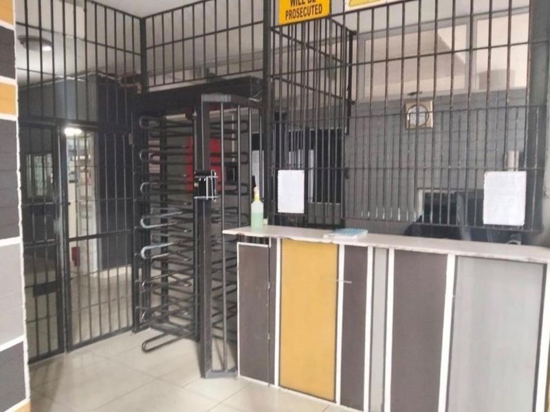 A secure building entrance area featuring a reception counter and metal security turnstile access control.