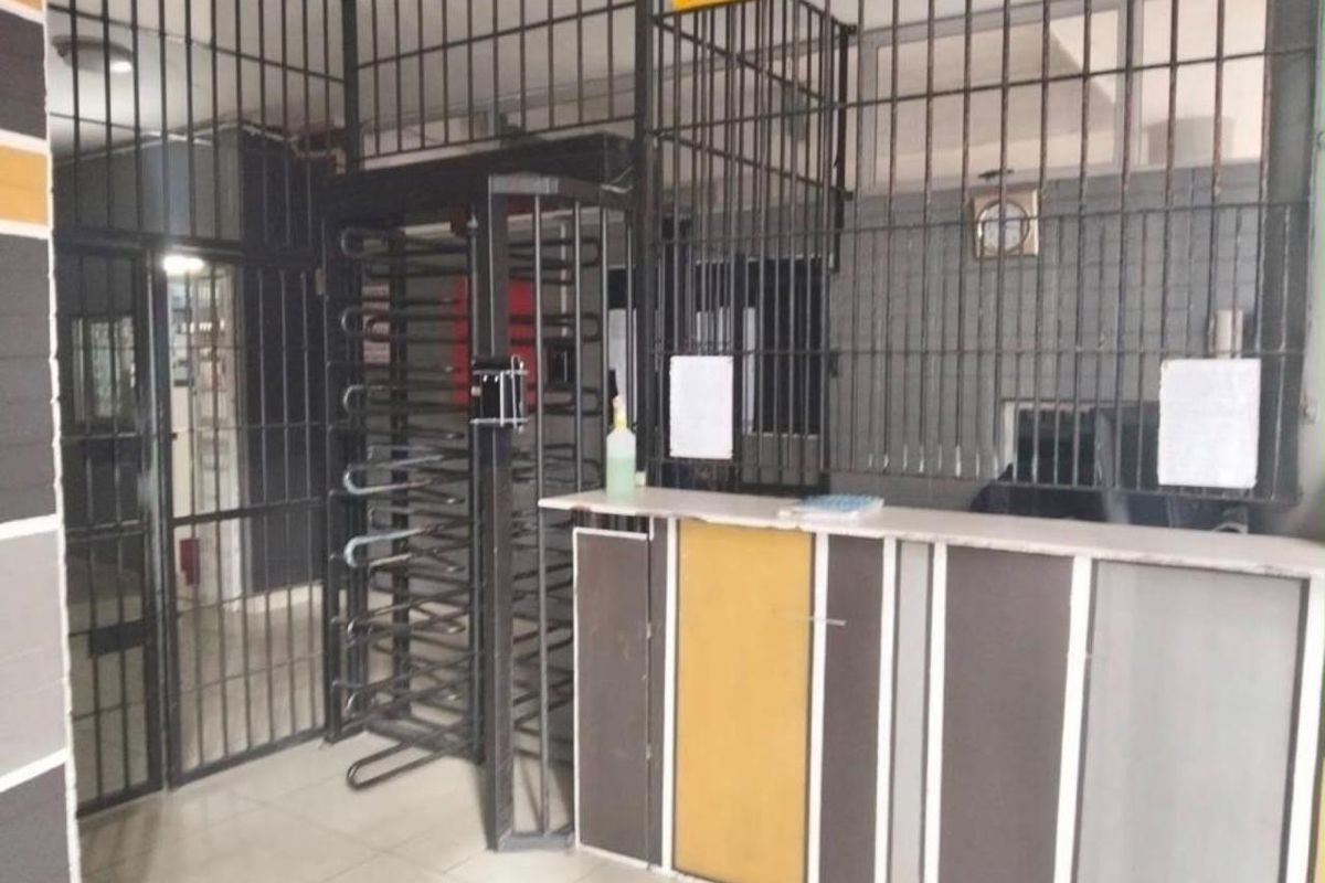 A secure building entrance area featuring a reception counter and metal security turnstile access control.
