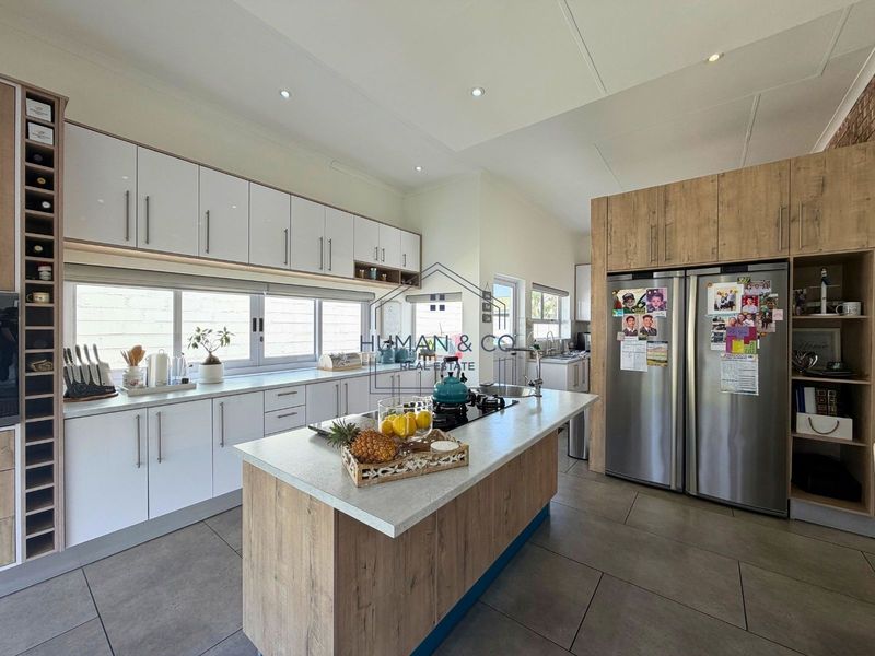 Modern kitchen featuring a central island, ample built-in cabinetry, stone countertops, and a gas hob, complemented by tiled flooring and recessed lighting.