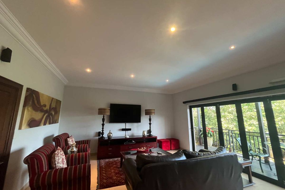 Spacious living room featuring recessed ceiling lighting, crown molding, and large glass sliding doors providing access to an outdoor balcony.